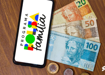 Celular com logo do Bolsa Família ao lado de cédulas de real.