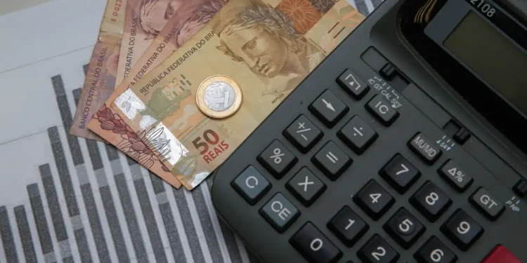 Imagem de uma calculadora com dinheiro do lado
