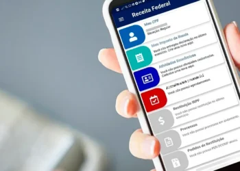 Pessoa segurando um celular com o aplicativo da Receita Federal aberto na tela.