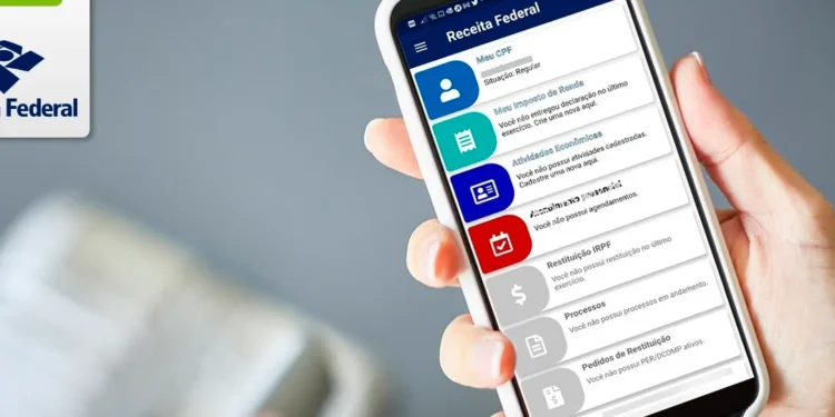 Pessoa segurando um celular com o aplicativo da Receita Federal aberto na tela.