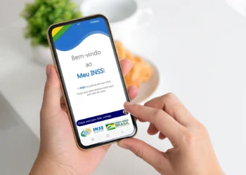 Pessoa acessando o aplicativo Meu INSS no celular para consultar benefícios e serviços previdenciários.