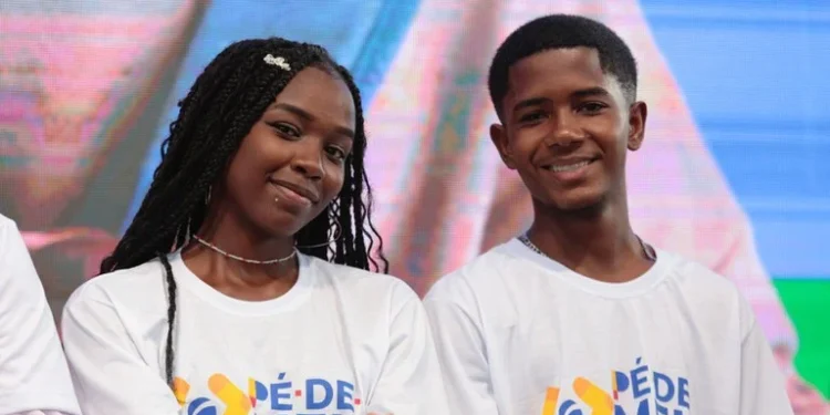 Jovens sorrindo durante evento do Pé-de-Meia, com camisetas do programa.