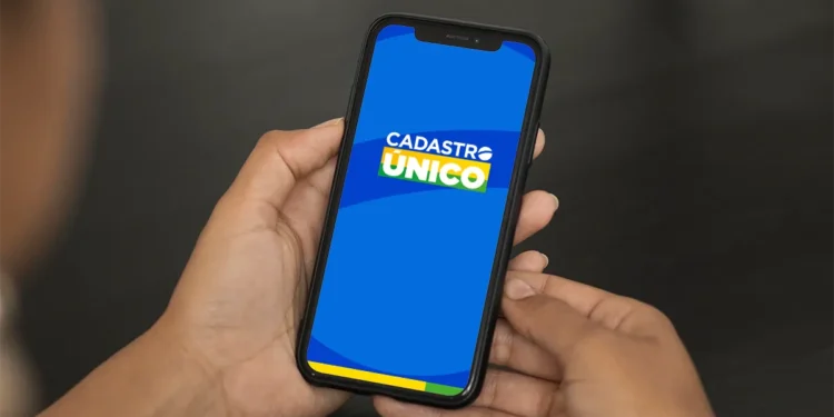 Mão segurando um celular com a tela exibindo o aplicativo do Cadastro Único.
