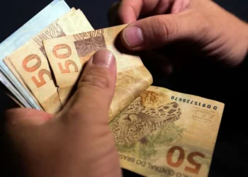 Pessoa segurando cédulas de R$ 50 e R$ 100, representando o pagamento do PIS/PASEP que será depositado na conta de milhares de brasileiros na próxima semana