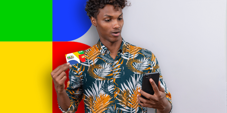 Homem surpreso segura cartão do Bolsa Família e celular em frente a fundo colorido