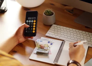 Empreendedor analisando suas finanças pessoais com calculadora e anotações.