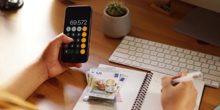 Empreendedor analisando suas finanças pessoais com calculadora e anotações.