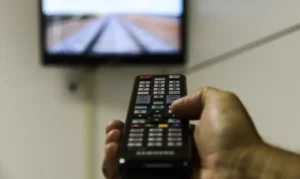 pessoa usando controle remoto para ligar a televisão digital