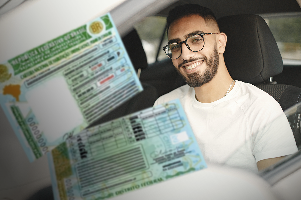 Homem sorridente dentro do carro exibindo sua CNH em papel