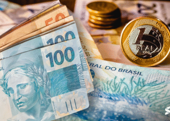 Cédulas e moedas de real brasileiro empilhadas, representando finanças pessoais.