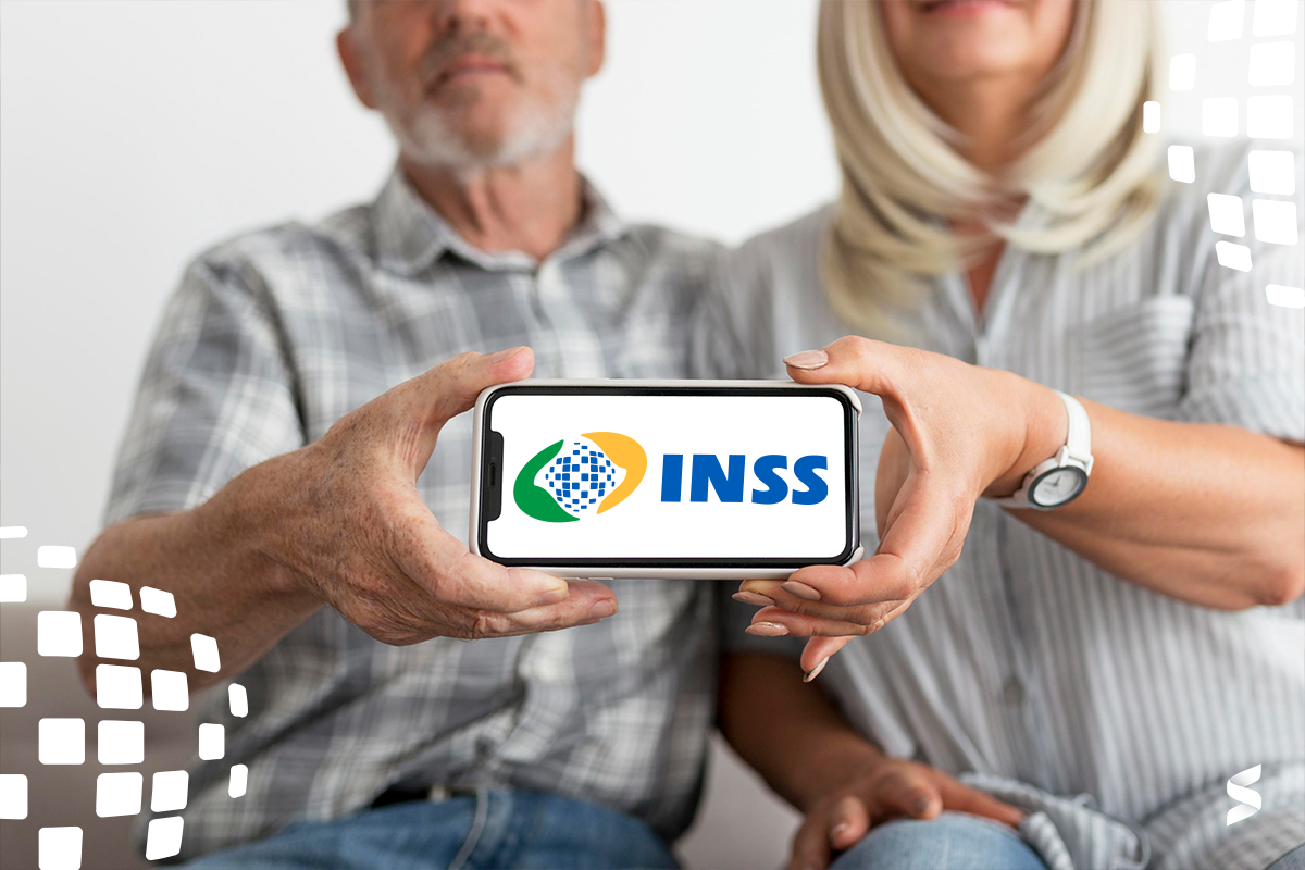 Casal de idosos segura celular com logo do INSS, simbolizando acesso digital a informações de pagamento.