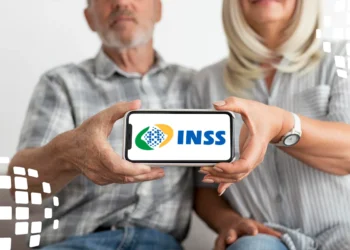 Casal mais velho segurando um celular com o logo do INSS na tela.