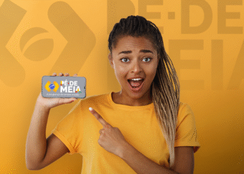 Jovem mulher segurando celular com o logo do programa Pé-de-Meia na tela, apontando para ele.