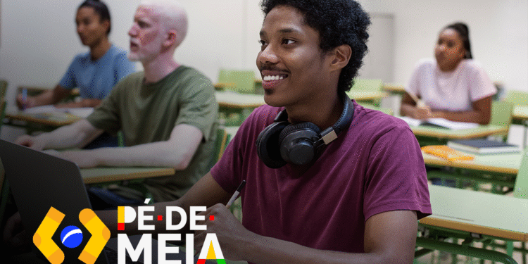Estudante atento e feliz em sala de aula, utilizando laptop e participando das aulas com apoio do Pé-de-Meia