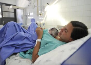 Mãe segurando seu recém-nascido na cama do hospital, simbolizando o direito à licença-maternidade.
