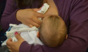 Mãe amamentando seu bebê, simbolizando o direito à licença-maternidade.
