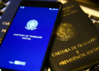 Carteira de Trabalho digital no celular e física sobre mesa, representando direitos dos trabalhadores CLT