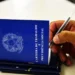 Pessoa preenche informações em uma Carteira de Trabalho e Previdência Social