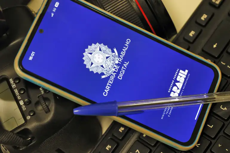 Aplicativo da Carteira de Trabalho Digital exibido na tela de um smartphone sobre teclado