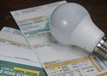 Lâmpada LED sobre contas de luz mostrando economia na tarifa social