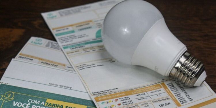 Lâmpada LED sobre contas de luz mostrando economia na tarifa social
