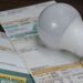 Lâmpada LED sobre contas de luz mostrando economia na tarifa social