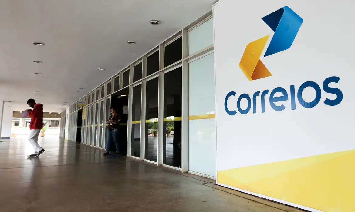 Fachada da agência dos Correios com pessoas entrando e saindo.