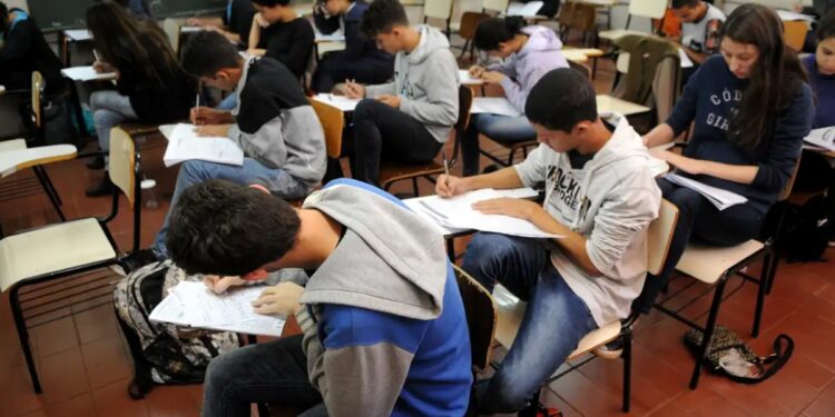 Estudantes concentrados fazendo uma prova em sala de aula.
