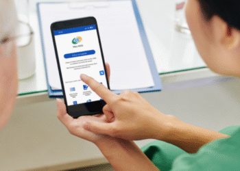 Imagem de um aplicativo do INSS sendo mostrado em um smartphone, alertando para a falsa convocação de aposentados por telefone para a prova de vida.