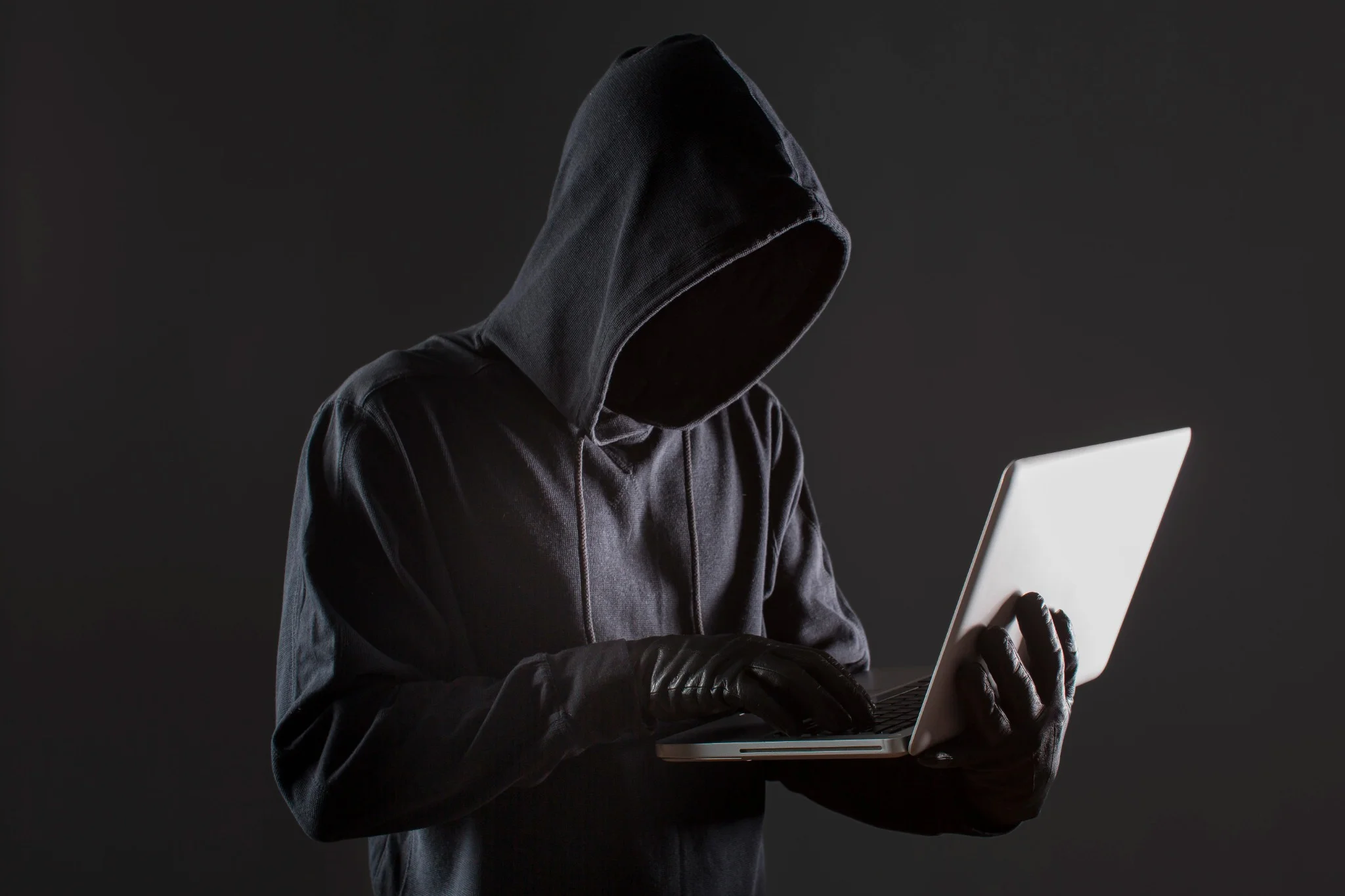 Hacker usando luvas e laptop, simbolizando ameaças cibernéticas