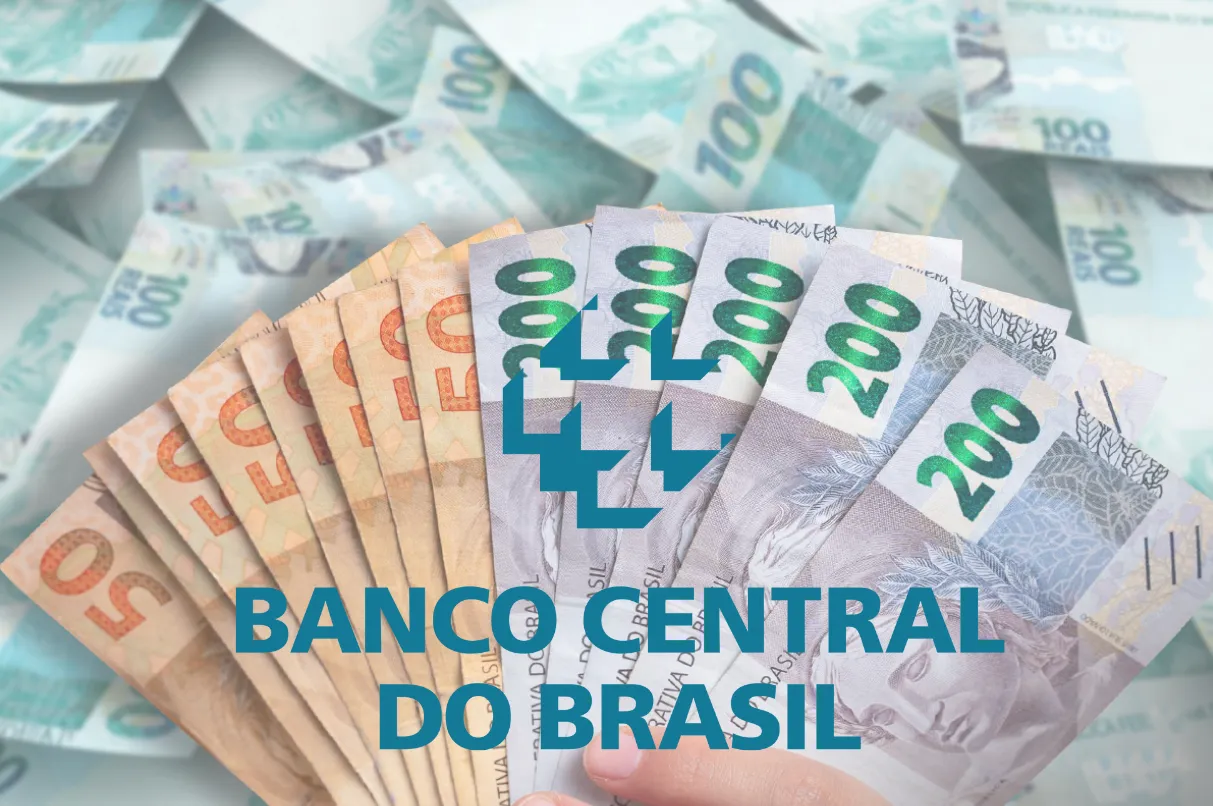 Notas de real brasileiro em mãos com o logo do Banco Central do Brasil em destaque.