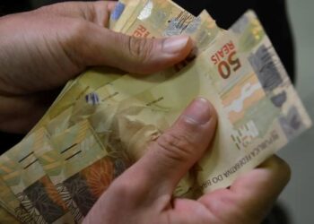 pessoa contando notas de cinquenta reais, representando o reajuste do salário mínimo no Brasil em 2025