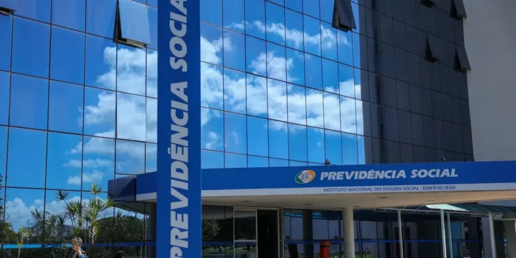 Fachada do prédio da Previdência Social com céu azul refletido nas janelas, simbolizando o INSS.