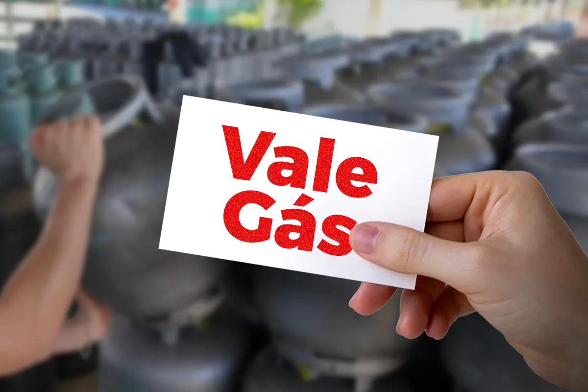 Pessoa segurando um cartão com os dizeres “Vale Gás” em meio a botijões, simbolizando o benefício do Auxílio Gás 2025.