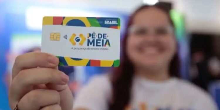Jovem sorridente segura cartão "Pé-de-Meia" com frase "A poupança do ensino médio", fundo colorido