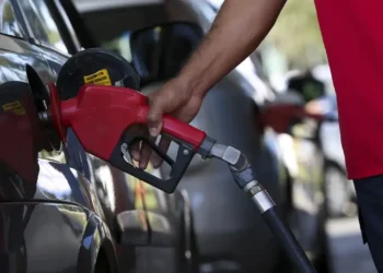 Imagem de um frentista abastecendo um carro com gasolina, simbolizando o impacto da nova composição nos preços dos combustíveis.