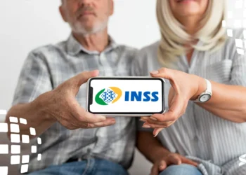 Casal de idosos segurando um celular com o logo do INSS na tela, representando o uso digital dos serviços do INSS.