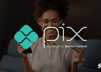 Pessoa segurando celular com a logo do Pix e cartão de crédito sorrindo.