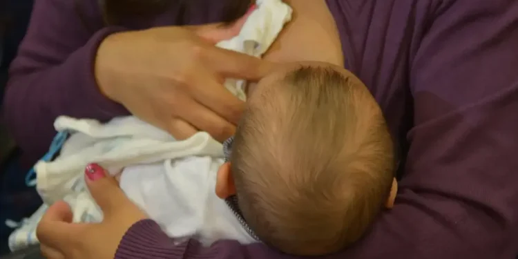 Imagem de uma mãe amamentando seu bebê, representando o vínculo entre a trabalhadora e o direito ao salário-maternidade.
