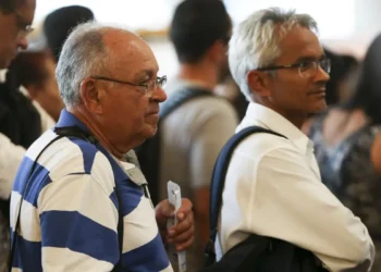 "Homens idosos em uma fila de atendimento, aguardando para resolver questões relacionadas ao INSS."