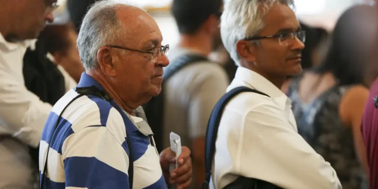"Homens idosos em uma fila de atendimento, aguardando para resolver questões relacionadas ao INSS."