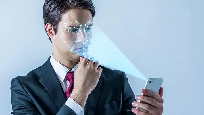 Pessoa utilizando biometria facial em um smartphone, representando os novos objetivos da regra de biometria do INSS.