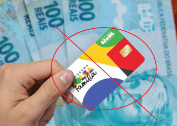 Imagem ilustrativa sobre o bloqueio do Bolsa Família em junho, com um cartão do programa sendo destacado com um X vermelho, ao fundo notas de 100 reais.