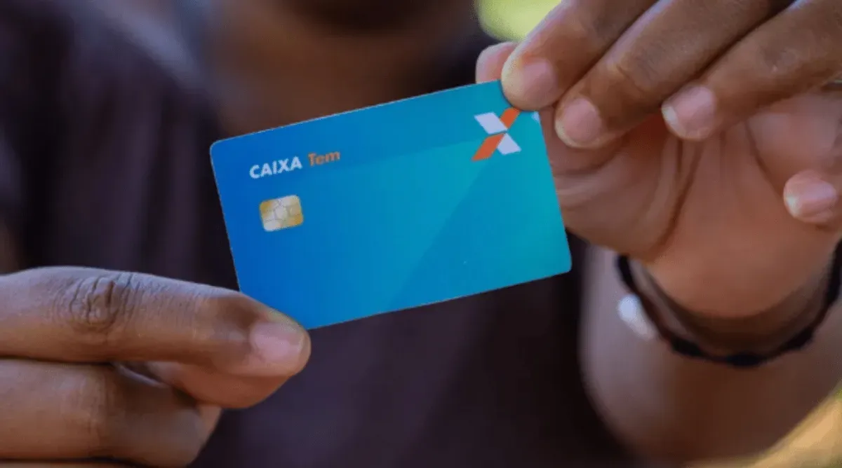 Pessoa segurando o cartão Caixa Tem para pagamento na maquininha.