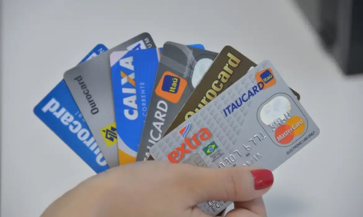 Pessoa segurando diversos cartões de crédito de diferentes instituições