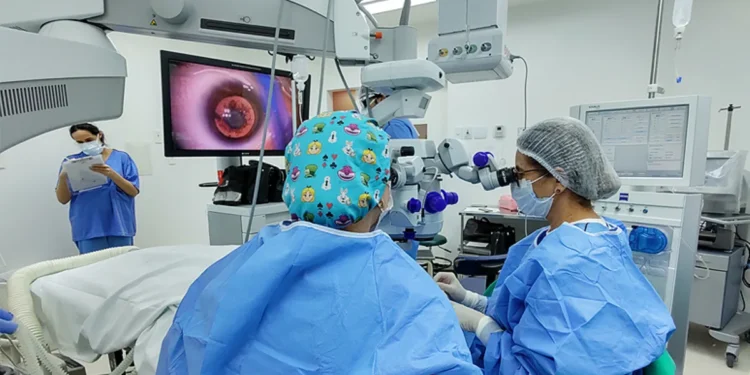 Equipe médica realizando cirurgia de catarata com equipamento especializado em ambiente hospitalar.