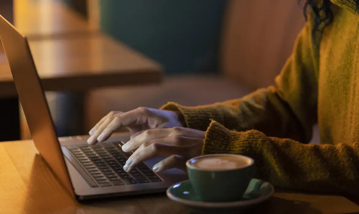 Pessoa digitando no laptop, representando a importância de proteger informações pessoais online.