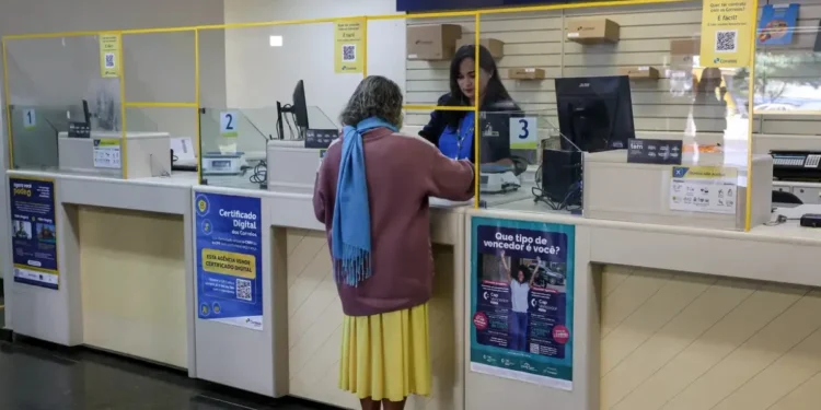 Pessoa sendo atendida nos Correios para consulta sobre cobrança indevida do INSS
