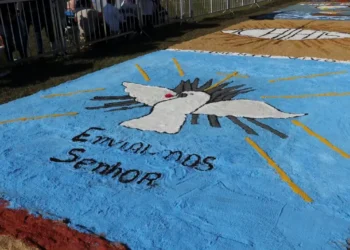 Imagem colorida de um tapete de Corpus Christi, com uma pomba branca em destaque e a inscrição 'Enviados ao Senhor'.