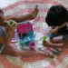 Crianças brincando no chão com brinquedos de Play-Doh em ambiente doméstico.